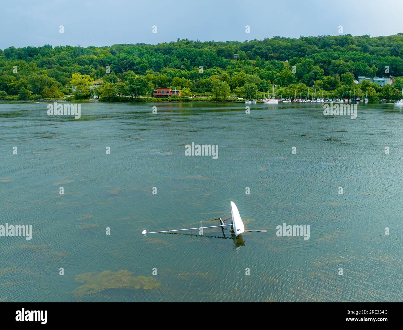 Small capsized sail boat on lake after an afternoon summer storm. Stock Photo