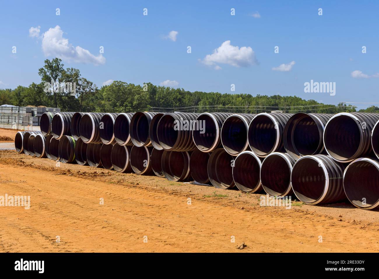 Construction site has stacks of a industrial sized black plastic pipes ...