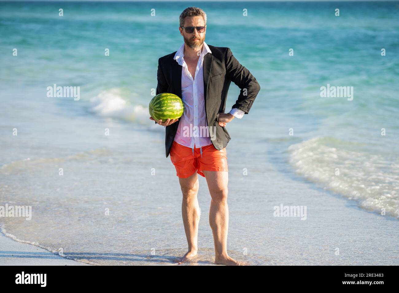 Businessman in suit with watermelon in sea. business man on summer vacation. businessman in wet suit at the beach. Summer business dreams. Successful Stock Photo