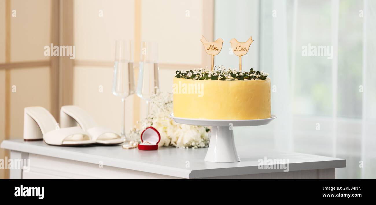 Stand with beautiful wedding cake on table in room Stock Photo