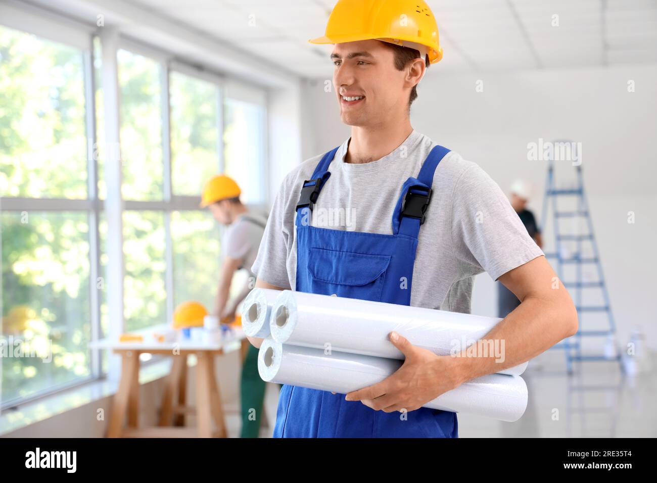 Male builder with wallpapers in room Stock Photo Alamy