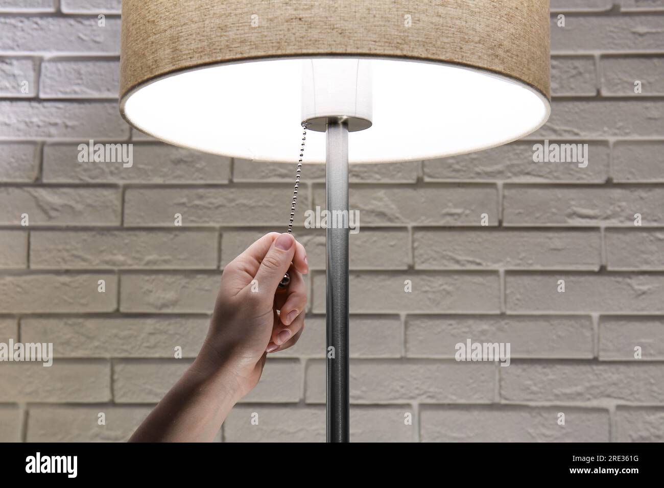 Woman turning on lamp in dark room, closeup Stock Photo