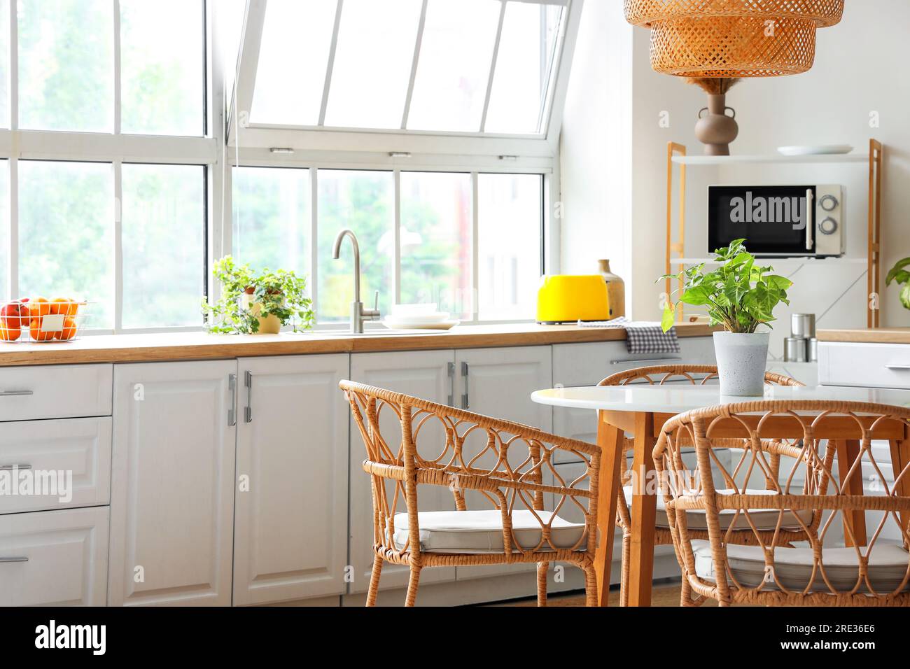 Interior of light kitchen with white counters, dining table and big ...