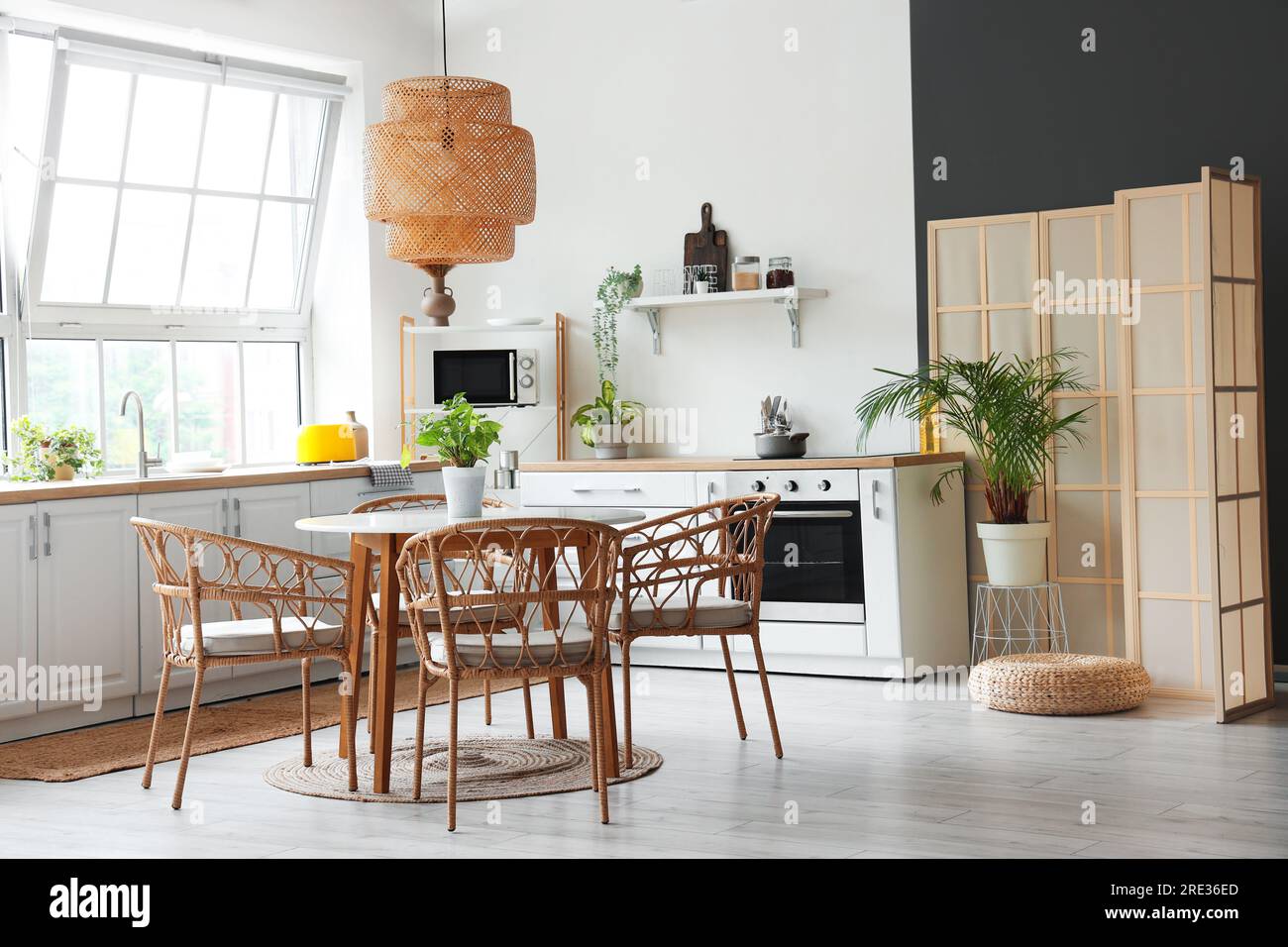 Interior of light kitchen with white counters, dining table and big ...