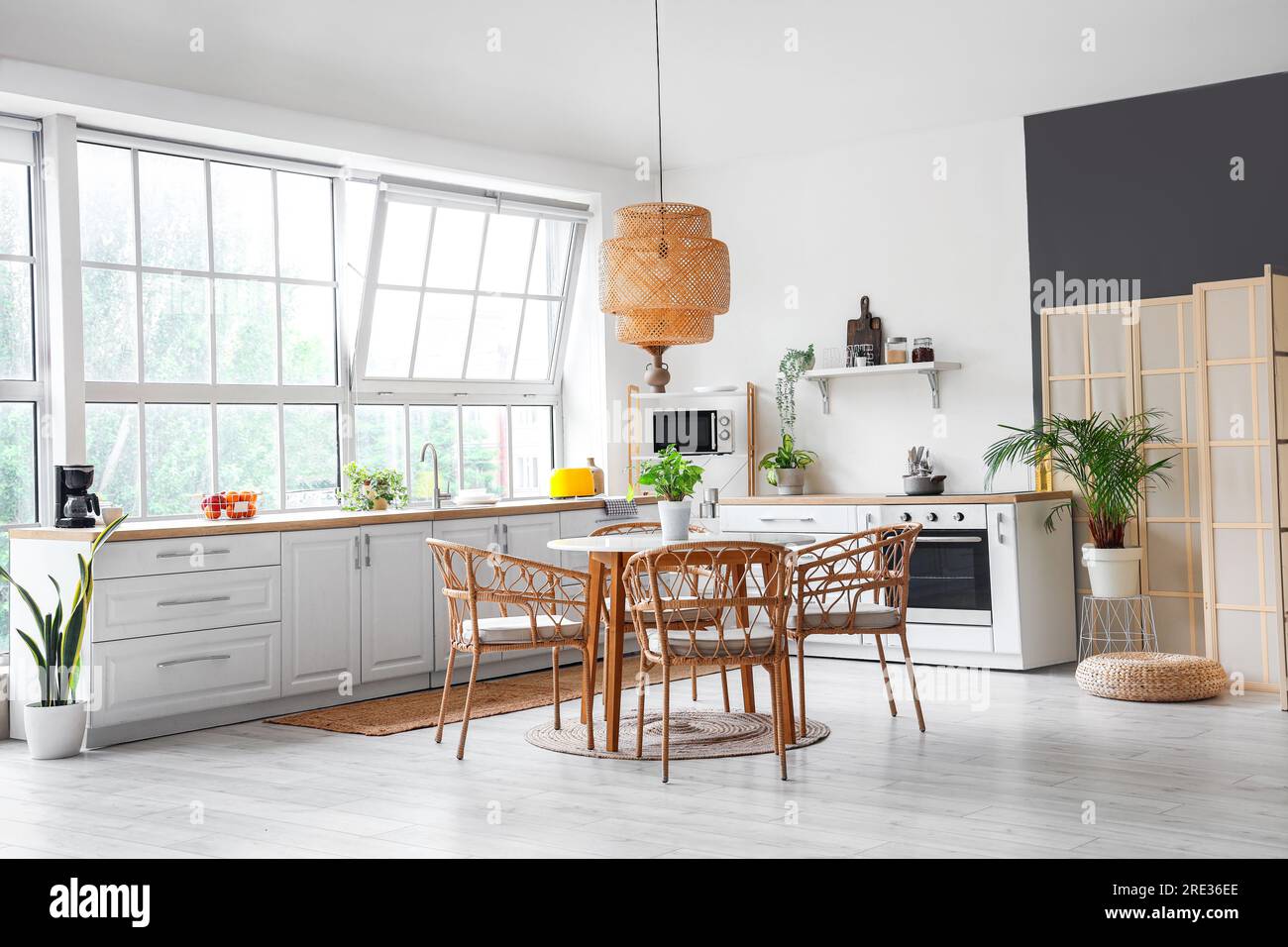 Interior of light kitchen with white counters, dining table and big ...