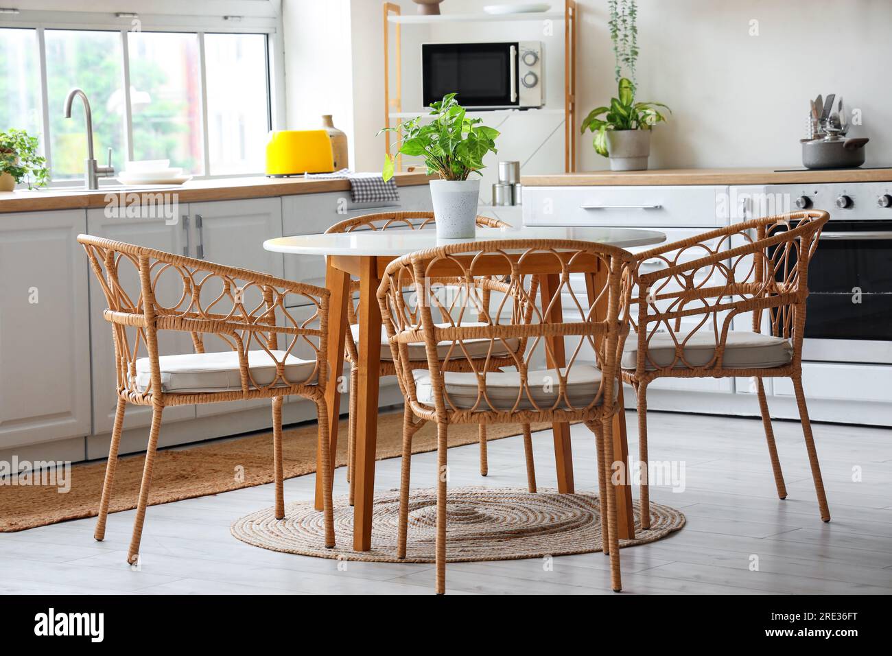 Interior of light kitchen with white counters, dining table and big ...