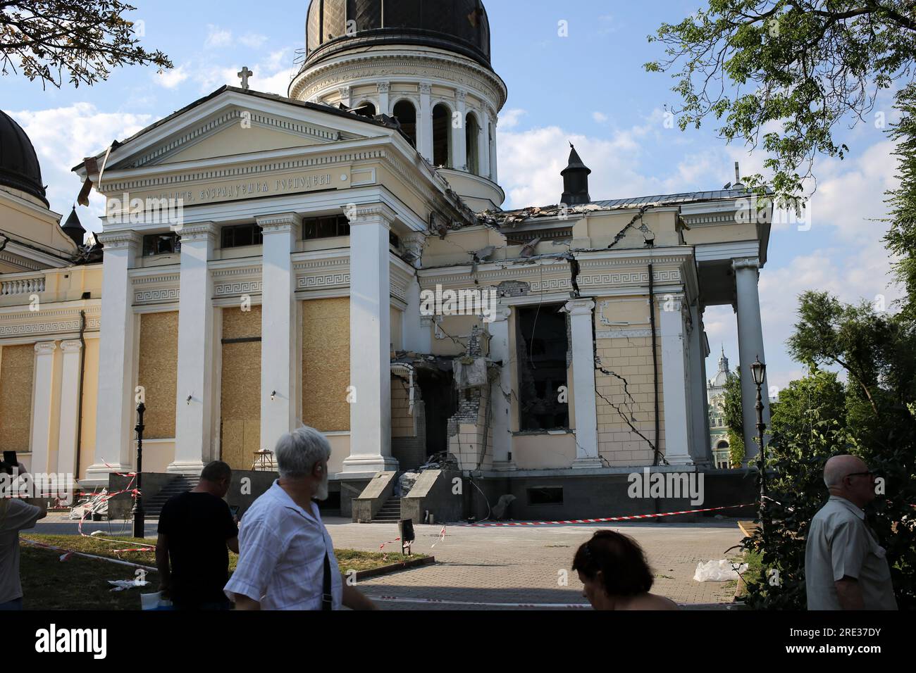 People stand near damaged Spaso-Preobrazhensky Cathedral (Transfiguration Cathedral) at the Cathedral Square. The day after the rocket attack in Odessa. According to the Operational Command 'South', the Russian forces fired missiles in Odesa on the night of July 23, 2023, with 5 types of missiles of all types based: Caliber, Onyx, Kh-22, Iskander-M. The port infrastructure, 6 residential buildings, and the Spaso-Preobrazhensky Cathedral (Transfiguration Cathedral) were damaged. So far 1 person has died and 22 people are injured. Among them are 4 children: 11, 12 years old and two 17-year-olds. Stock Photo