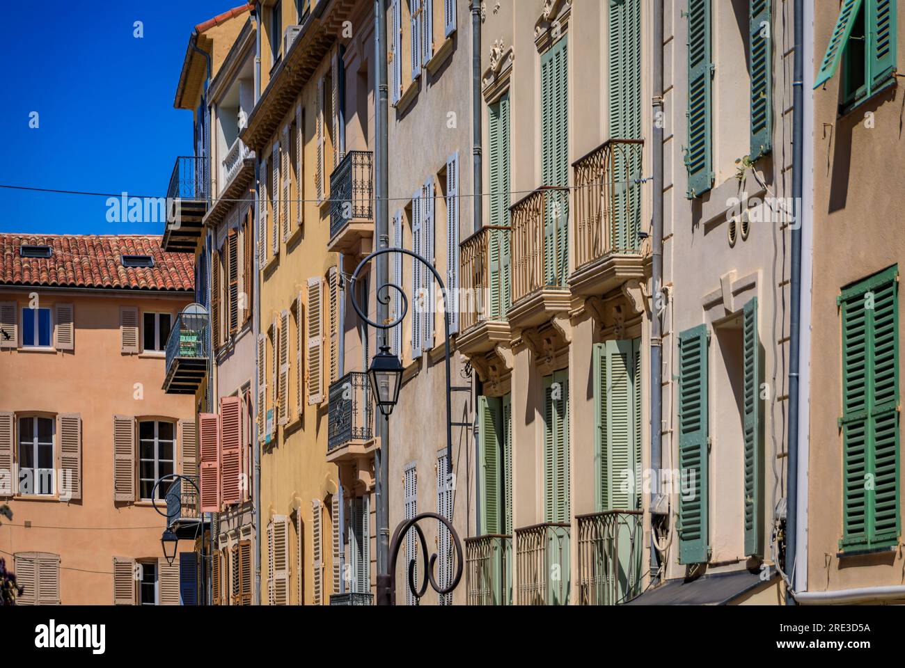 Traditional Mediterranean old houses with wooden shutters on a street near the local provencal market in old town or Vieil Antibes, South of France Stock Photo