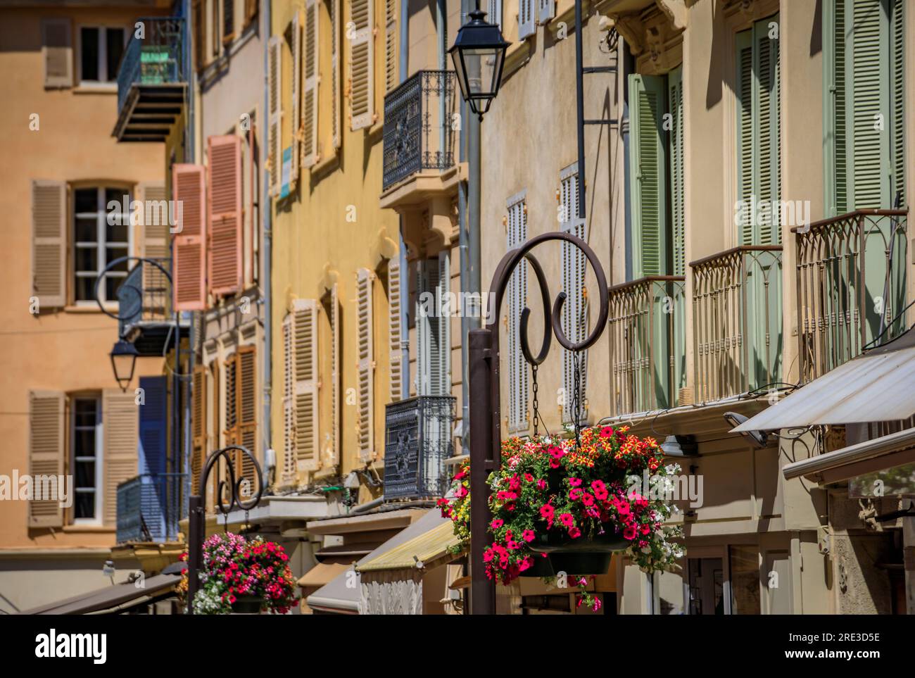 Traditional Mediterranean old houses on a street with flower pots near the local provencal market in old town or Vieil Antibes, South of France Stock Photo
