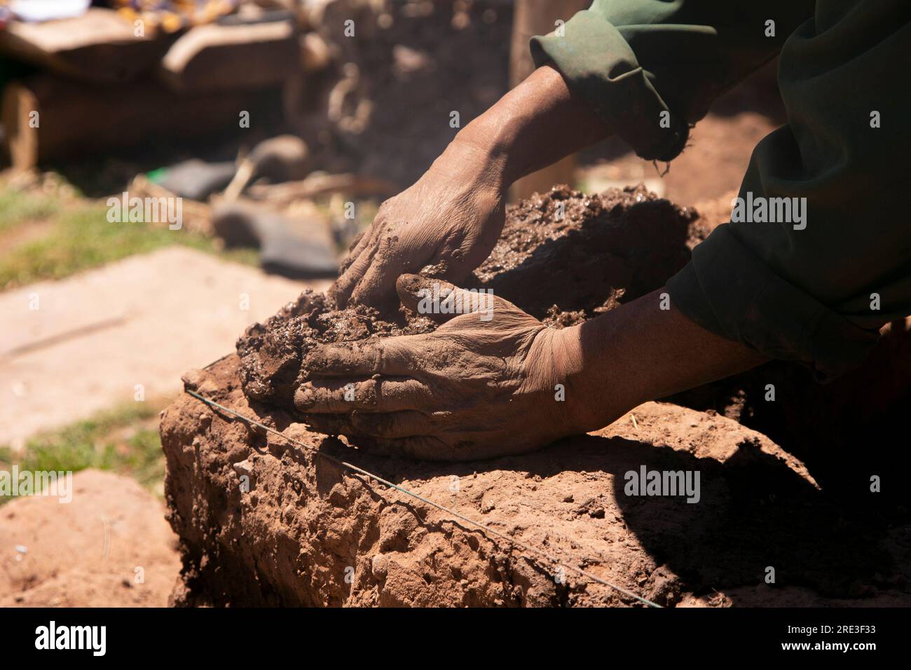 Man building with his hands an adobe house with adobe bricks and mud. Llachon region of Lake Titicaca in Peru. Stock Photo