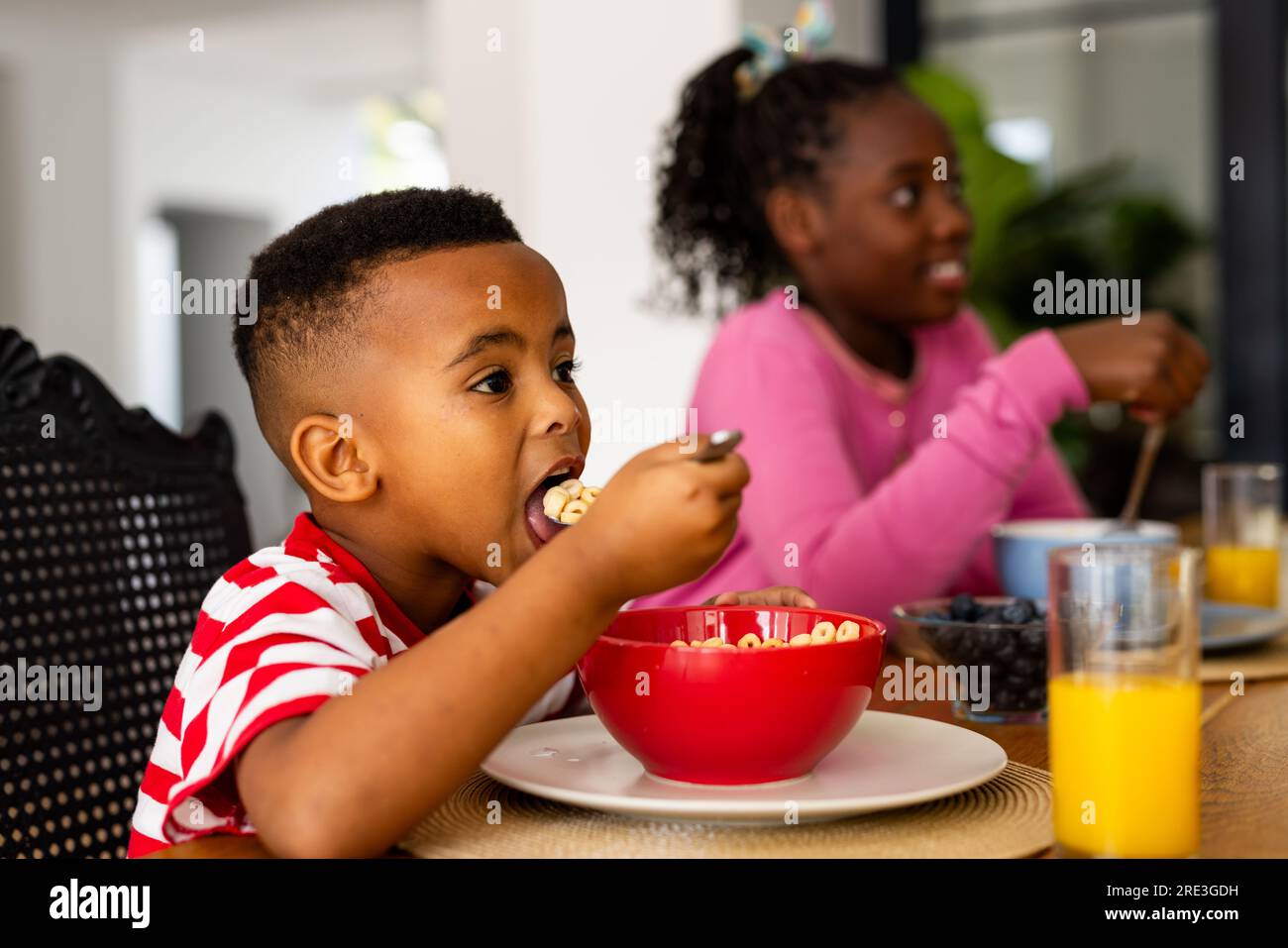 African american brother and sister eating breakfast in dining room at