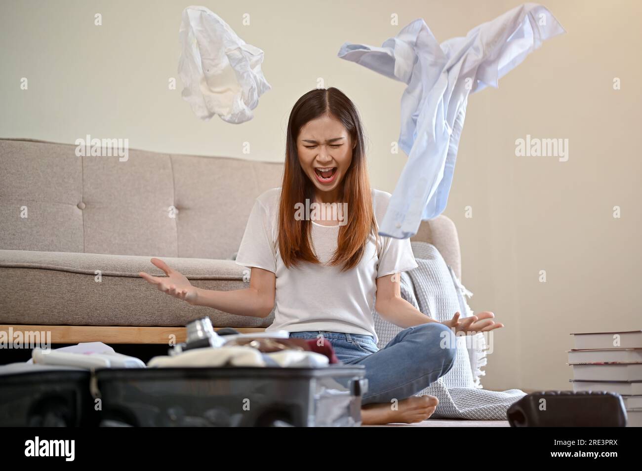 A crazy and furious young Asian girl screaming and throwing her clothes up in the air while