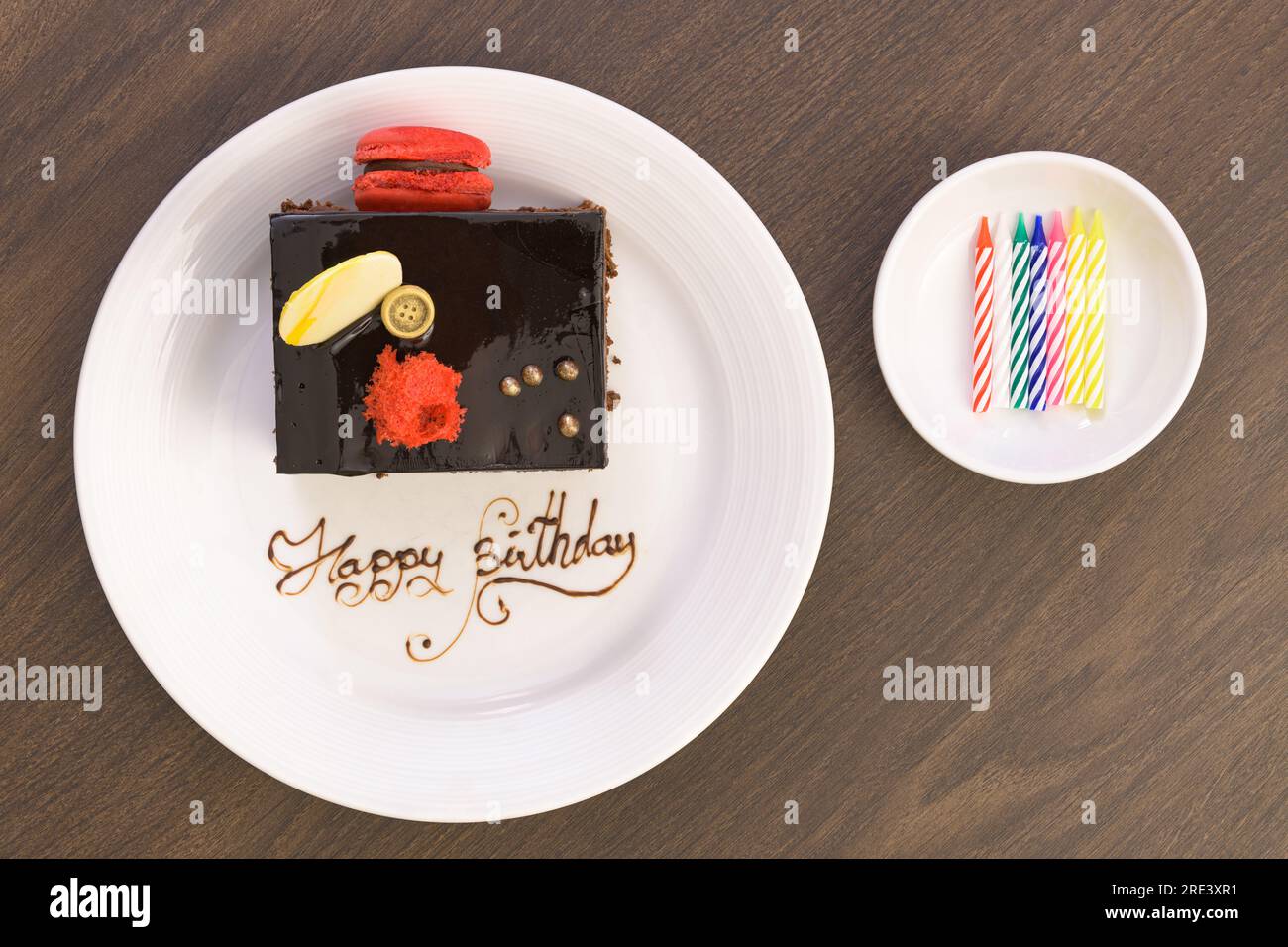 Birthday chocolate cake decorated with macarons and white chocolate on a  white plate with the words Happy Birthday Stock Photo - Alamy