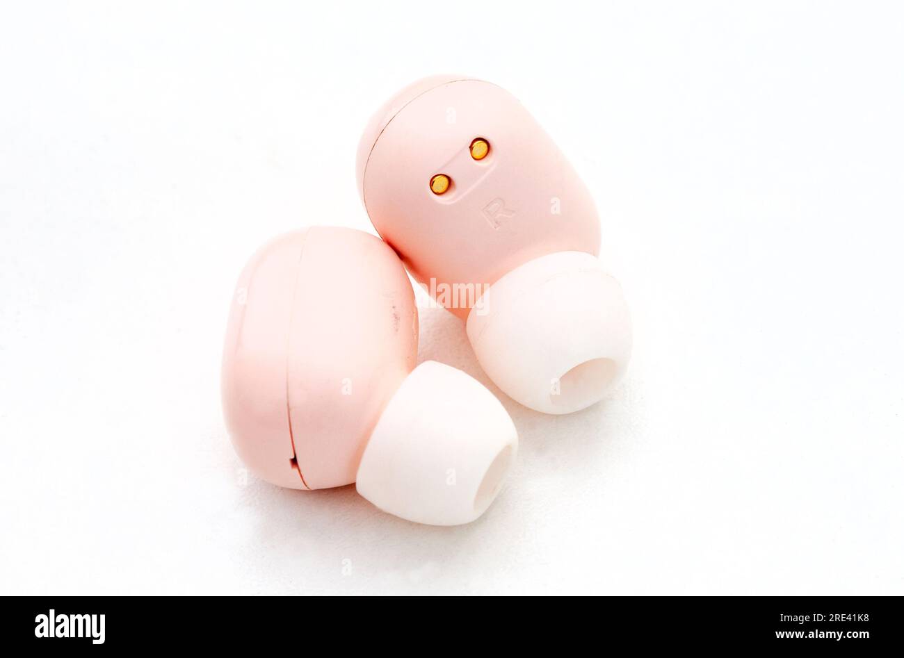 Light pink colored in-ear wireless earphones on white Stock Photo