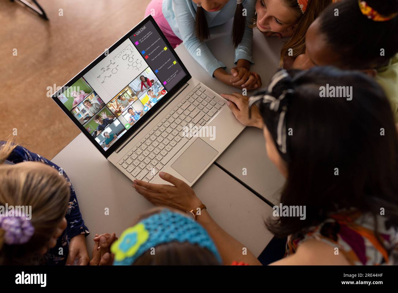 Multiracial teacher and students looking at laptop while studying online over video call on table Stock Photo