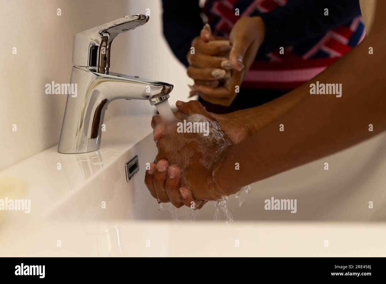 Midsection of african american mother and son washing hands in bathroom Stock Photo