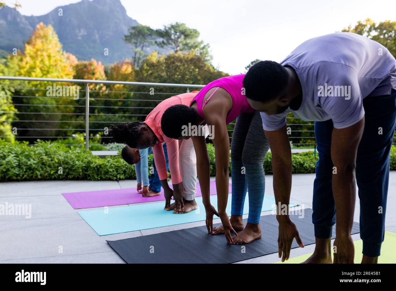 African american couple with son and daughter practicing yoga on sunny terrace at home Stock Photo