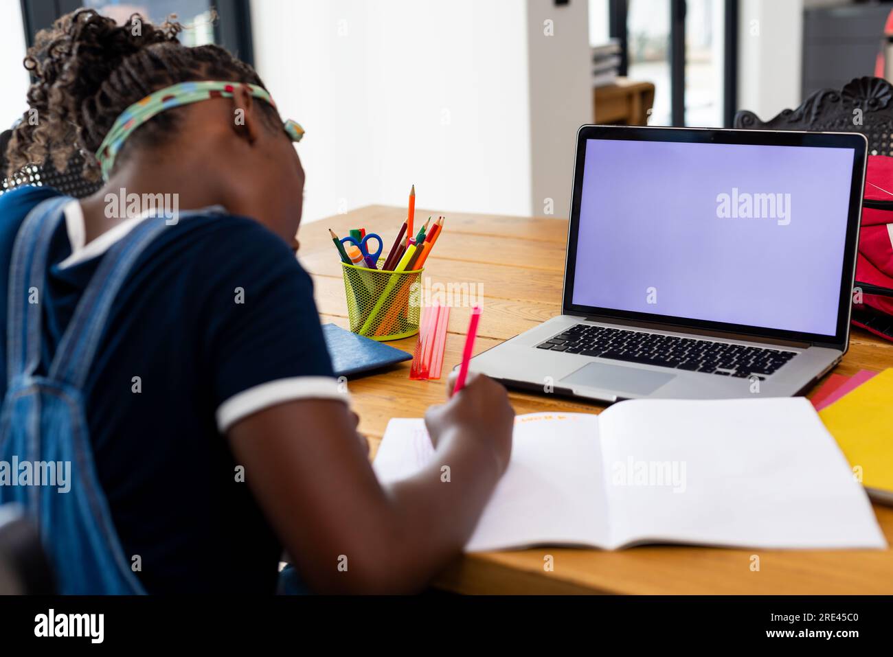 Back of african american girl learning online using laptop with copy ...