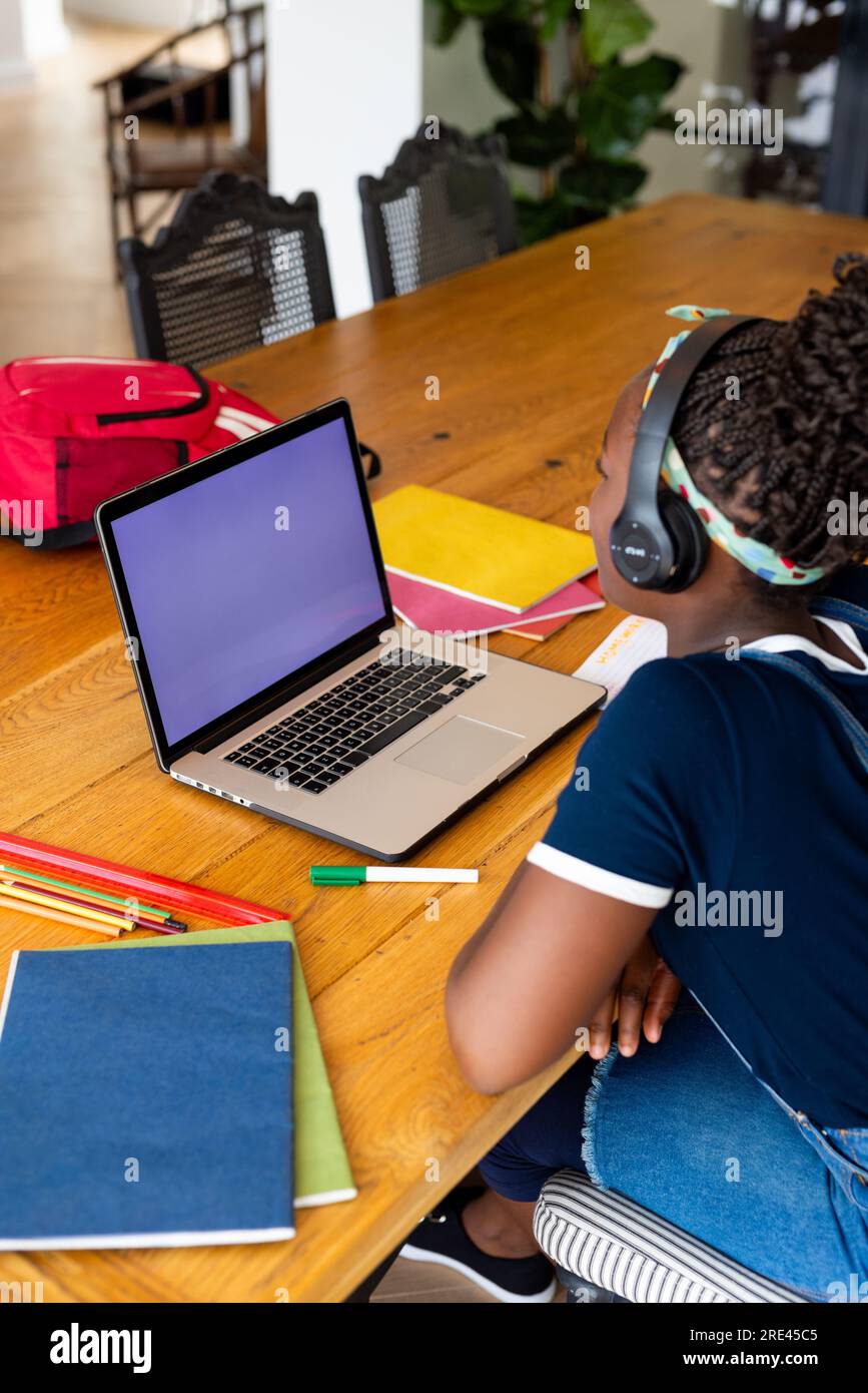 African american girl with headphones learning online using laptop with ...