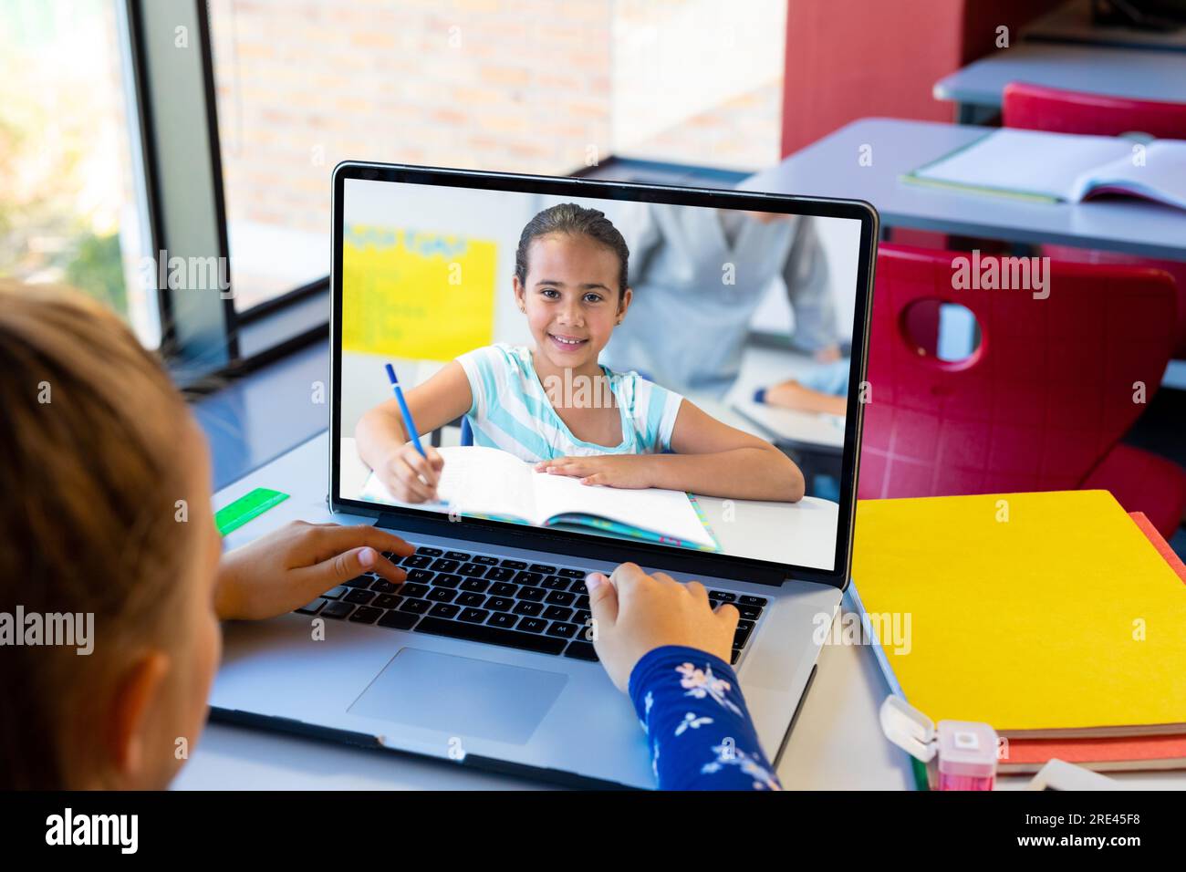 Rear view of caucasian girl using laptop while having a video call with ...