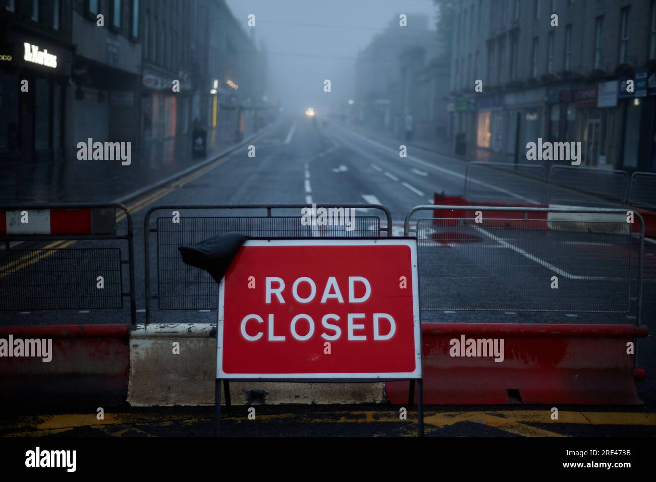 Road closed sign in empty city with street lights. Stock Photo