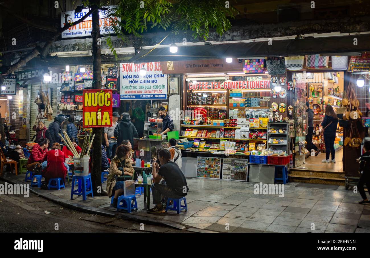 Vietnamese people sit at a pavement cafe at nighttime to drink sugarcane juice in central Hanoi, Vietnam. Stock Photo