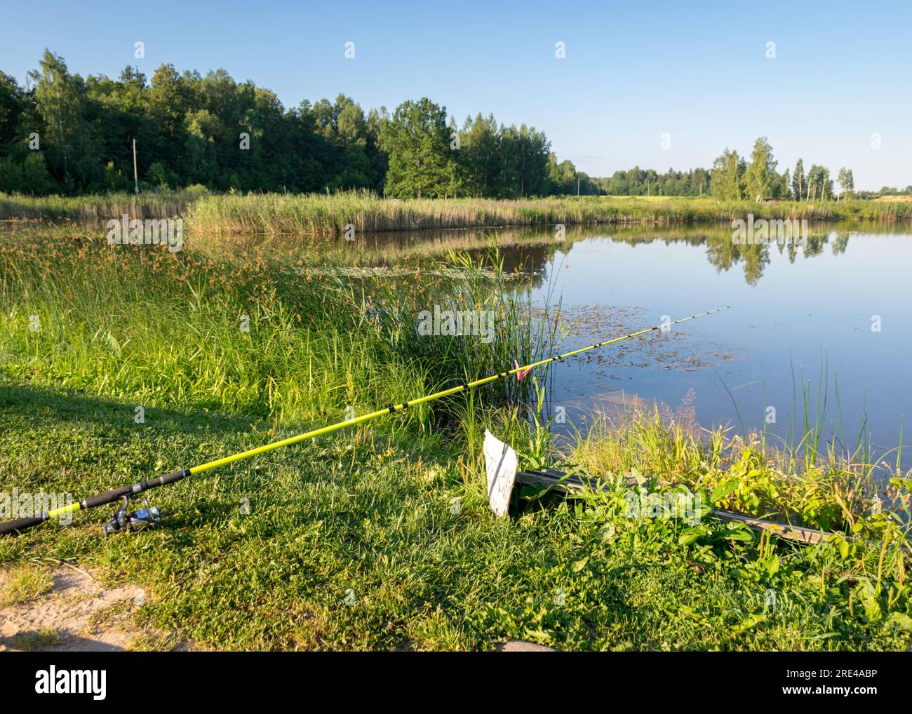 sunny summer landscape by the lake, fishing tackle in the foreground, calm  lake water, beautiful reflections in the water, summer Stock Photo - Alamy