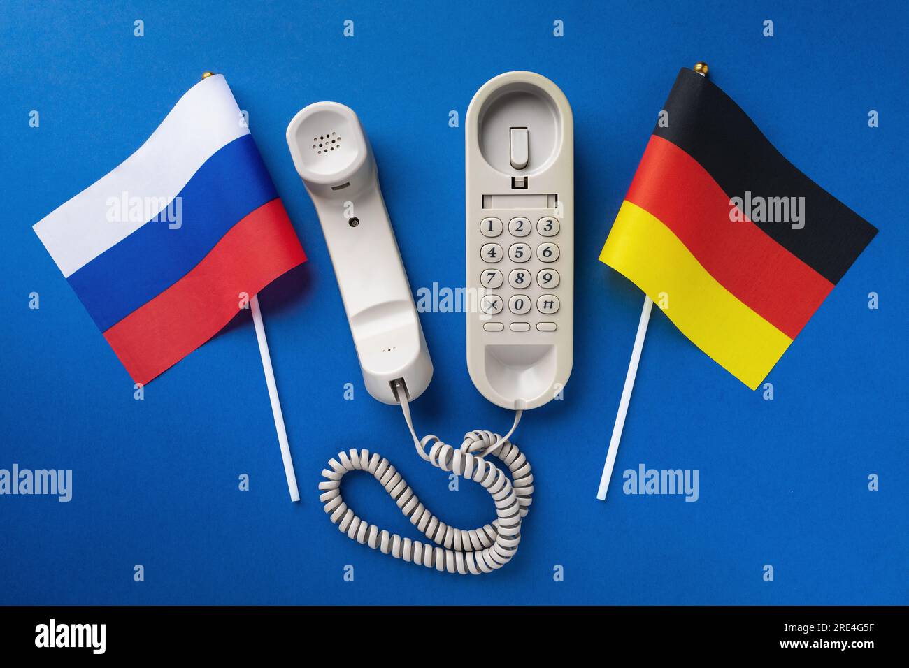 Old telephone and two flags on a blue background, a concept on the theme of telephone conversations between Russia and Germany Stock Photo