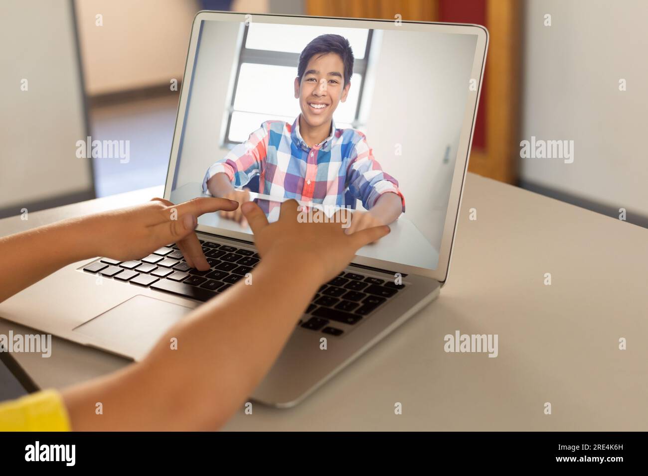 Mid section of a boy using laptop while having a video call with indian boy at home Stock Photo