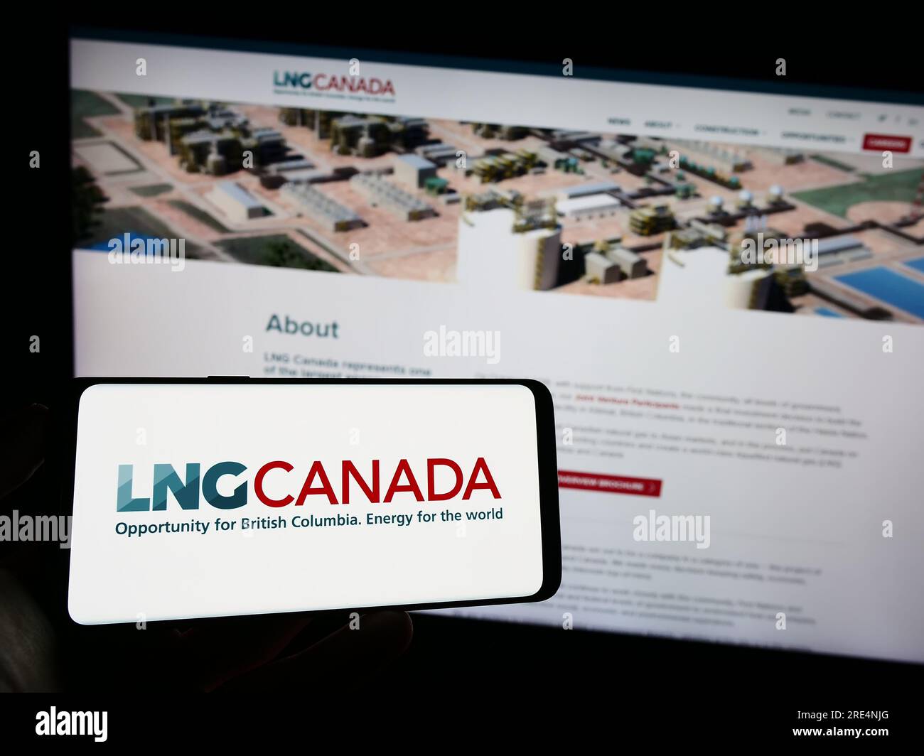 Person holding cellphone with logo of industrial energy project LNG Canada on screen in front of webpage. Focus on phone display. Stock Photo