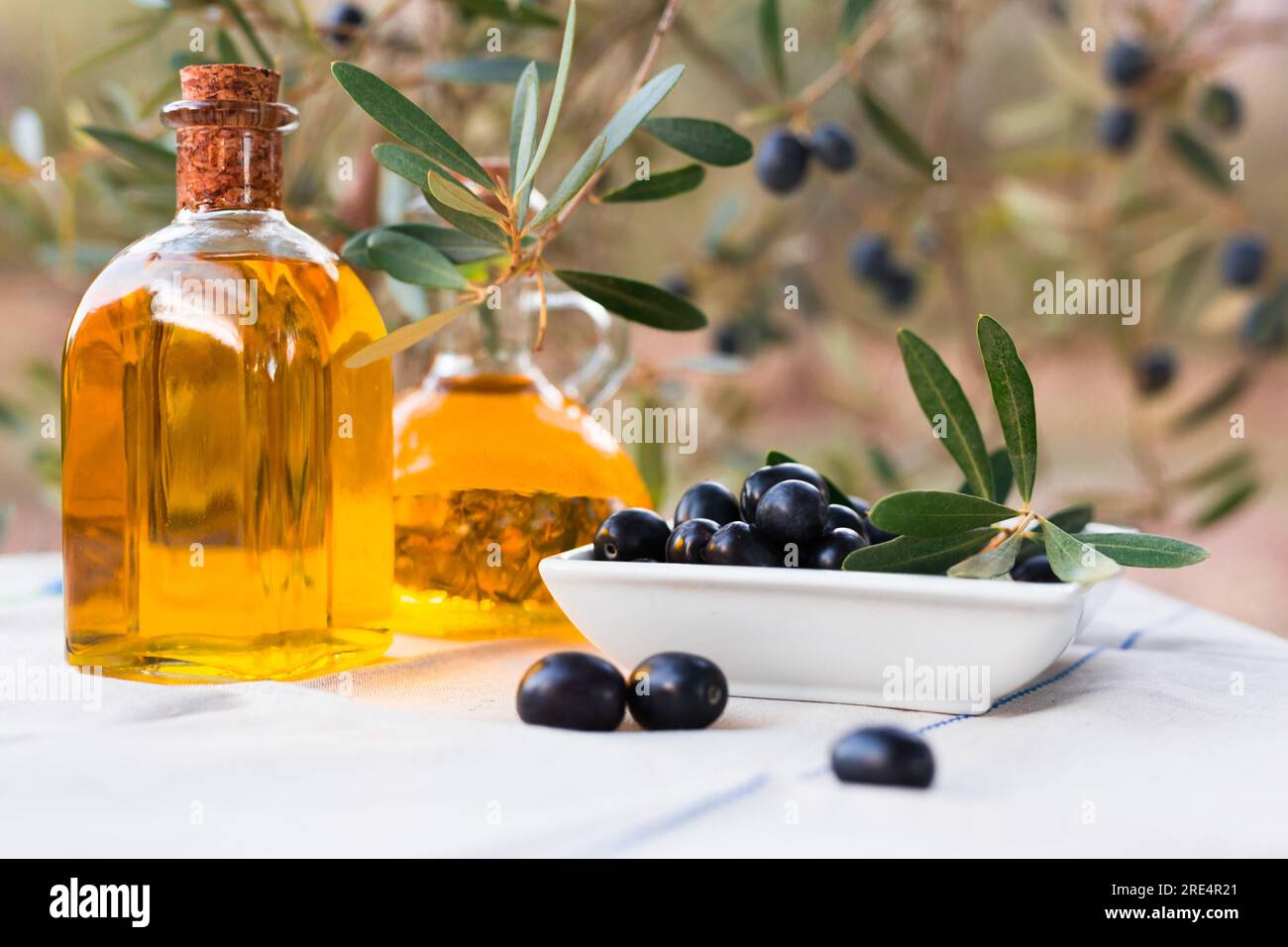 Black ripe olives, olive oil in a glass traditional bottle on table in ...