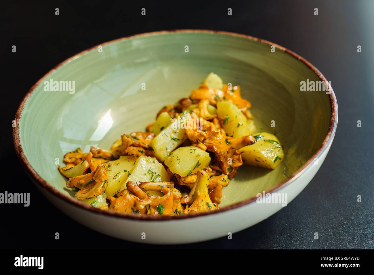 A bowl with a fresh summer seasonal vegetarian lunch. Fried chanterelles with boiled potatoes and herbs Stock Photo