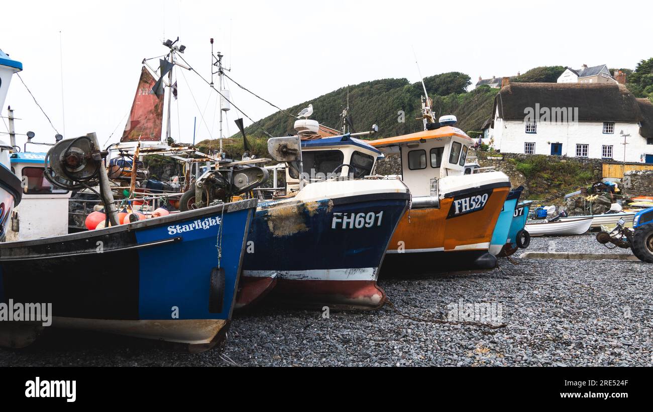 CADGWITH, CORNWALL, UK - JULY 1, 2023.  Traditional Cornish fishing boats out of the water and on the pebble beach at the popular tourist destination Stock Photo