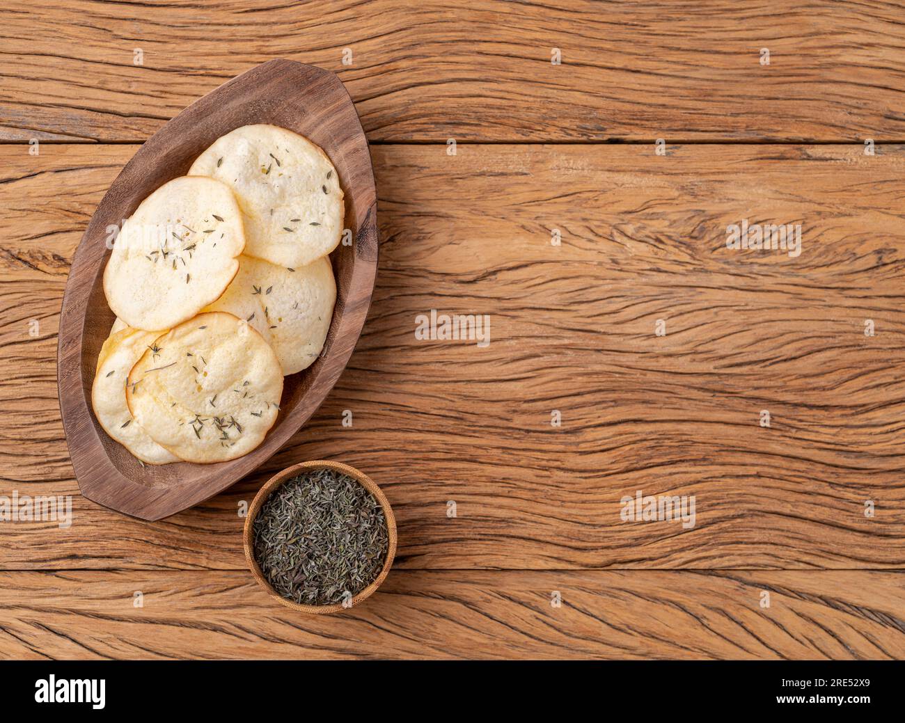 Smoked provolone cheese chips in a bowl with oregano over wooden table