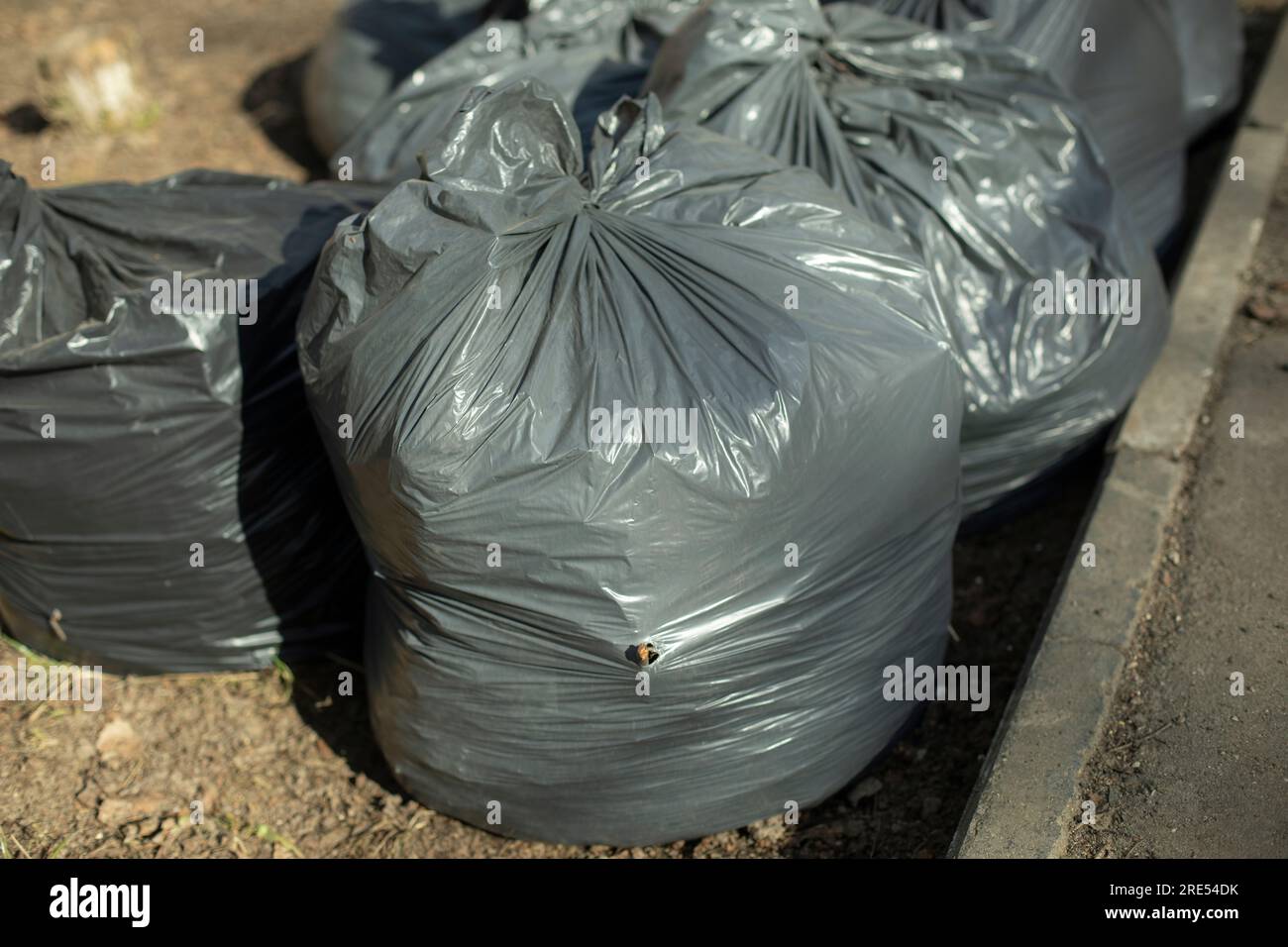 https://c8.alamy.com/comp/2RE54DK/garbage-black-plastic-bags-collected-garbage-in-yard-details-of-street-cleaning-2RE54DK.jpg