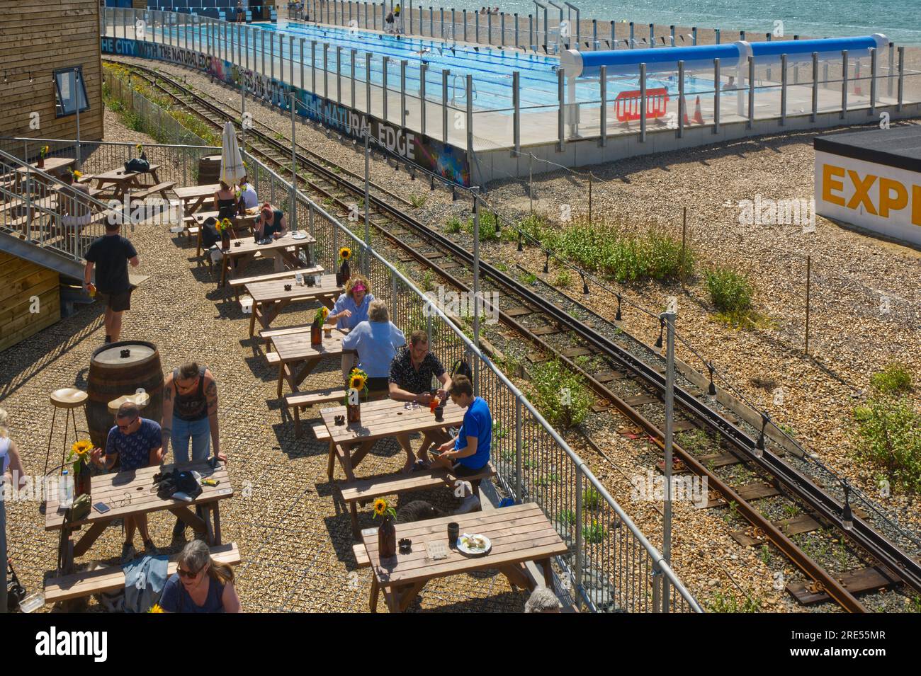 New swimming poo, cafe and restaurant on shingle beach at Brighton, East Sussex, England. With people in pool and cafe. Stock Photo
