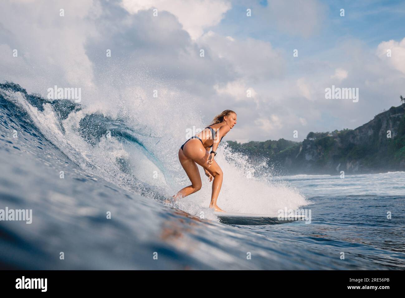 Surf girl on surfboard riding on ocean wave. Woman during surfing