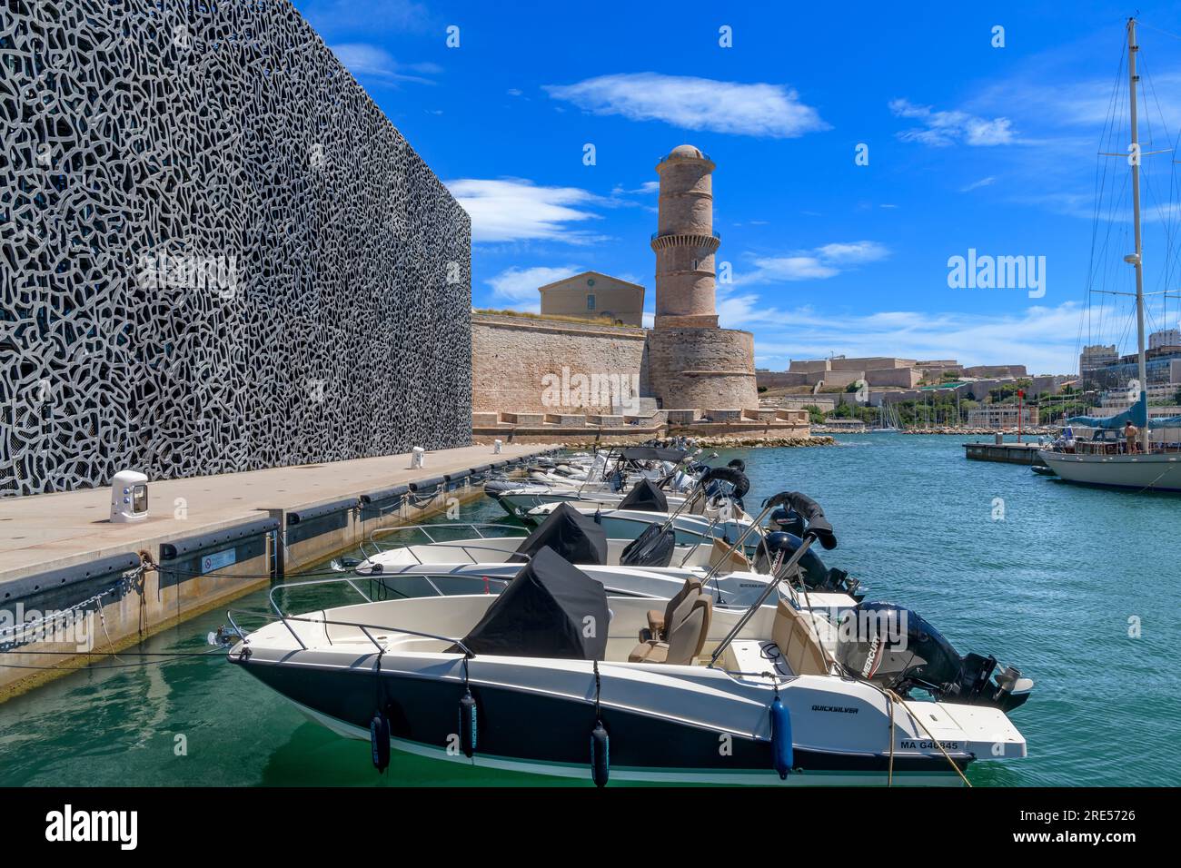 Rows of speedboats moored close the city of Marseille. Behind is the stone tower of Tour du Fanal, built in 1644 to guide ships into the old port. Stock Photo