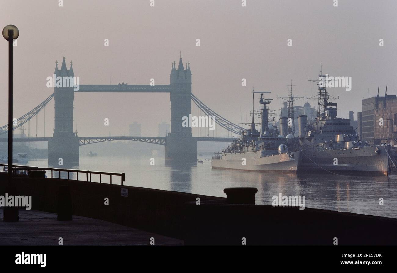 Royal Navy ships HMS Active moored alongside HMS Belfast on the River Thames by Tower Bridge. London. England. 21st May 1985 Stock Photo