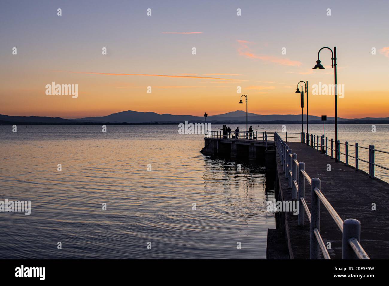 Lake with jetty at sunset. Relaxing Italian landscape at sunset in autumn. Trasimeno lake at sunset Stock Photo