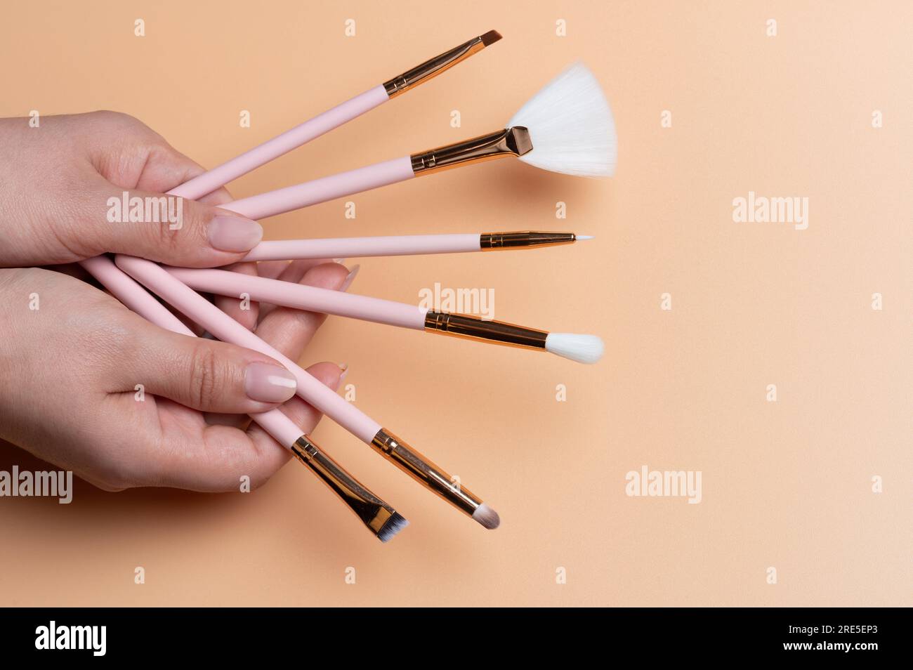 Make up artist theme. Different size brushes in woman hand on beigr color background Stock Photo