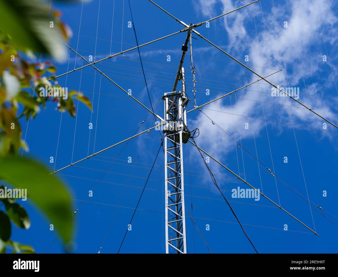 A closeup shot of a tall ham radio antenna against a blue sky