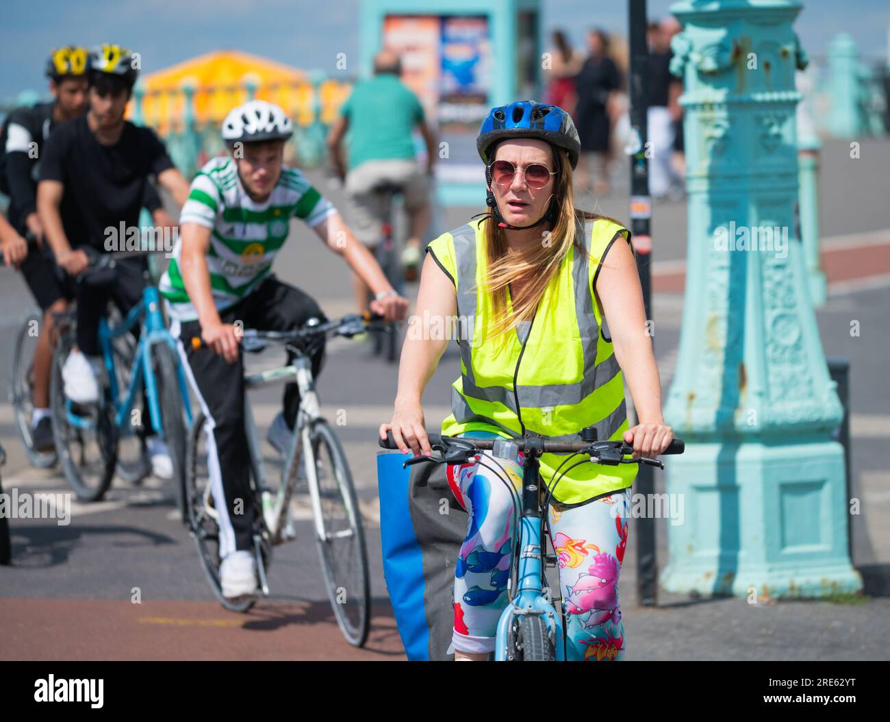 Group of cyclists riding bicycles in a cycle lane on the seafront promenade at Brighton, Brighton & Hove, East Sussex, England, UK. Stock Photo