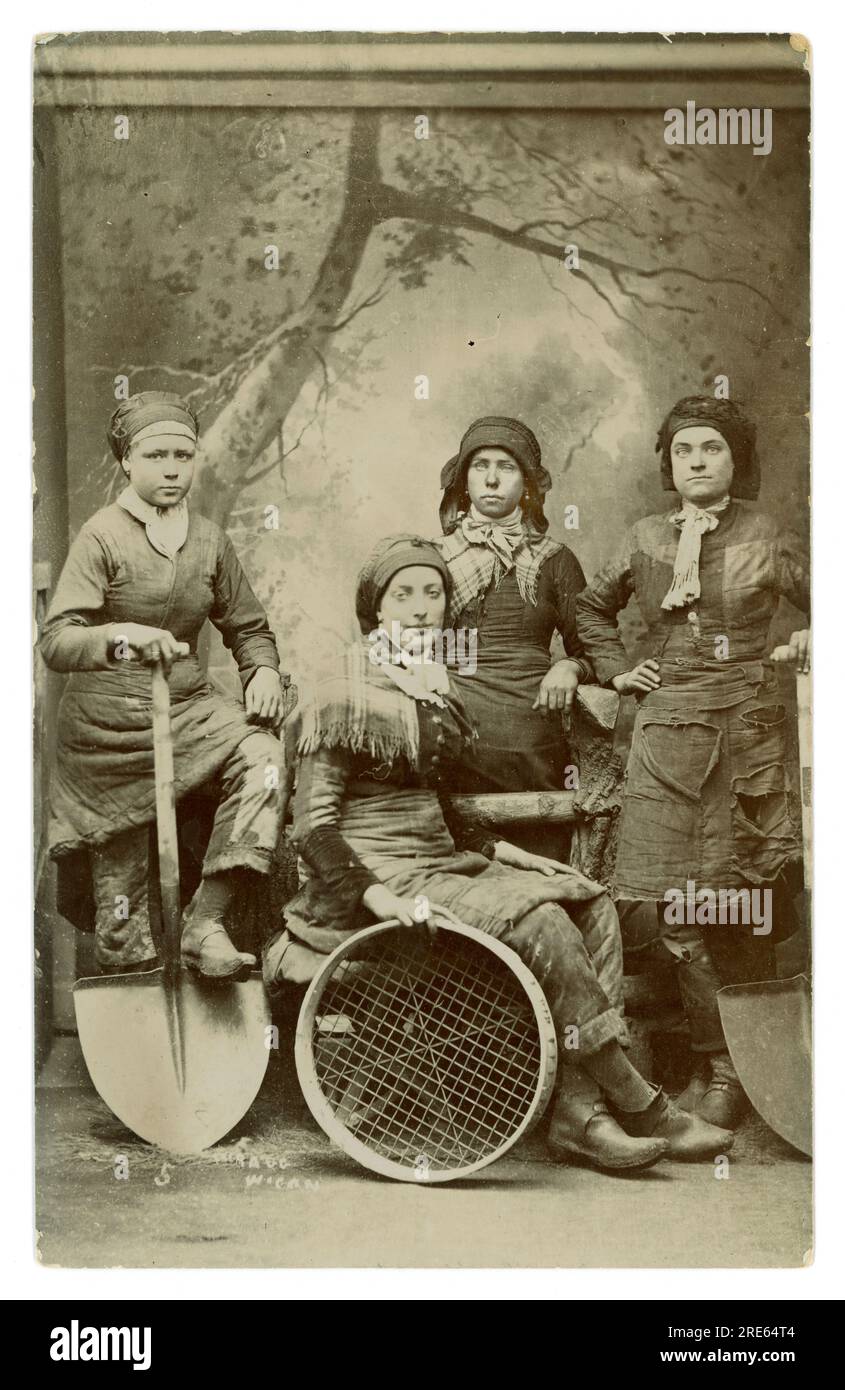 Original Victorian studio portrait printed as a souvenir postcard of Pit Brow girls and Screen Lasses with tools of trade, posted June 9th 1908 but photographed in 1887 by Herbert Wragg at an unknown coalfield in Wigan, Lancashire, England, U.K. Stock Photo