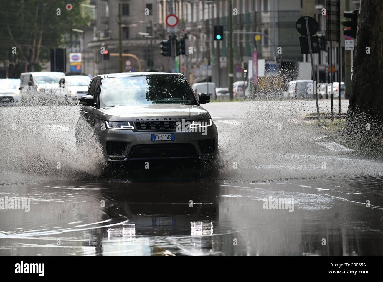 Milan, Italy. 25th July, 2023. A vehicle drives through a flooded street after thunderstorms in Milan, Italy, on July 25, 2023. While the southern two-thirds of Italy struggled under the oppressive heat, most of the northern area was pelted by thunderstorms and over-sized hail. Media reports said the emergency services in Milan had responded to more than 200 requests for help related to flooding, fallen trees, and damage to cars and homes, since a severe storm hit the city late Monday. Credit: Str/Xinhua/Alamy Live News Stock Photo