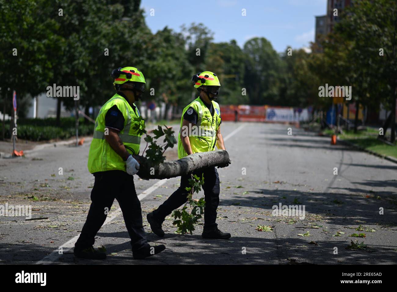 Milan, Italy. 25th July, 2023. Workers remove a fallen branch after thunderstorms in Milan, Italy, on July 25, 2023. While the southern two-thirds of Italy struggled under the oppressive heat, most of the northern area was pelted by thunderstorms and over-sized hail. Media reports said the emergency services in Milan had responded to more than 200 requests for help related to flooding, fallen trees, and damage to cars and homes, since a severe storm hit the city late Monday. Credit: Str/Xinhua/Alamy Live News Stock Photo