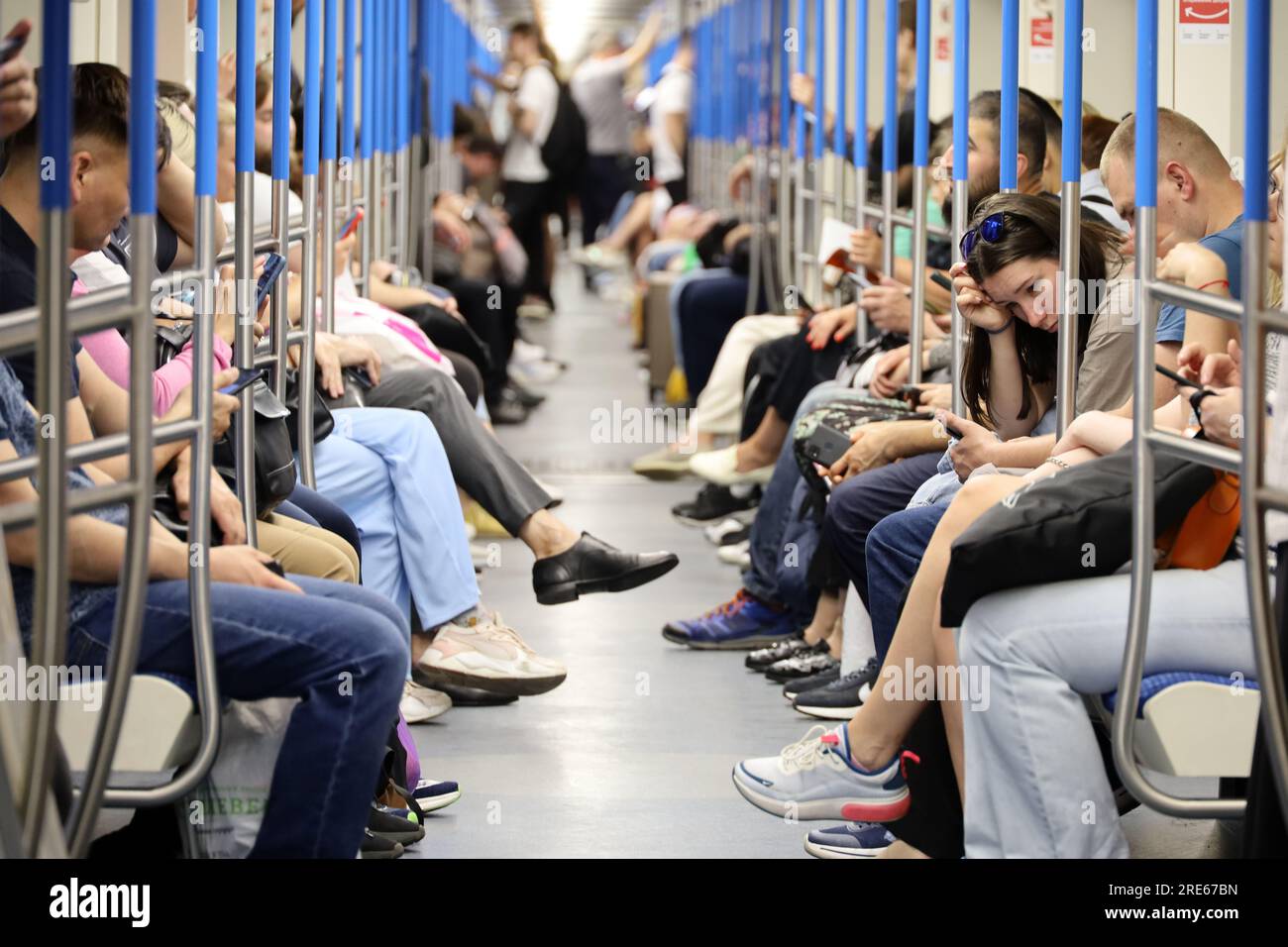 Crowd of people in a metro train in summer, passengers sits with smartphones. Interior of subway car Stock Photo