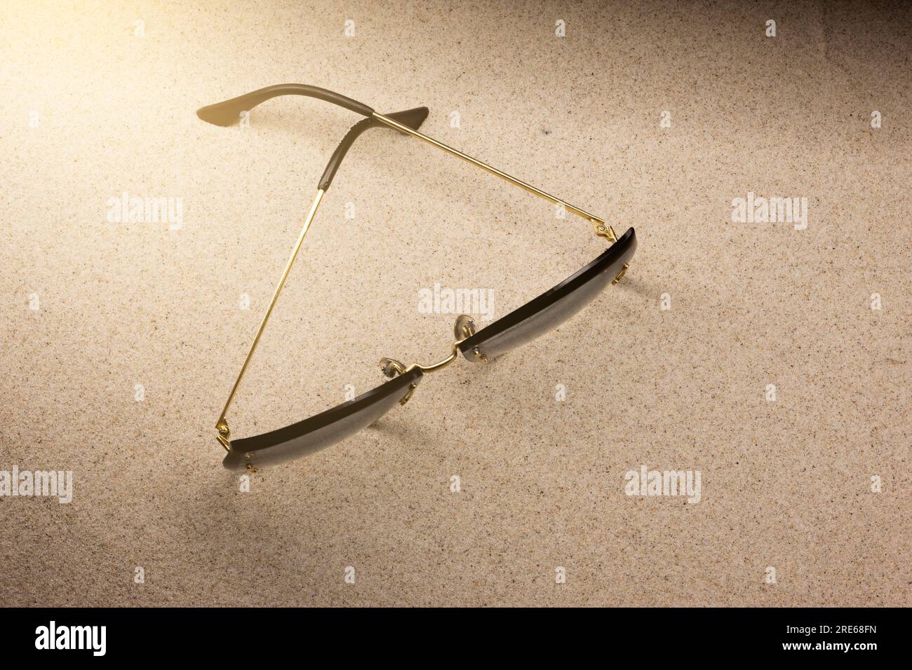 Women's beach sunglasses with golden frames lying on the sand in the