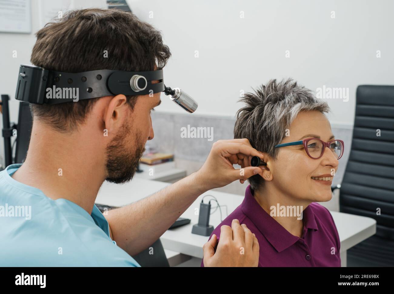 Otolaryngologist doing checkup of mid aged woman at modern medical center. Portrait of