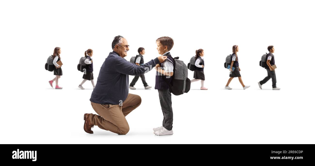 Grnadfather helping a boy getting ready for school and other children walking in the back isolated on white background Stock Photo